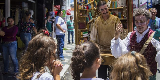 ação bibliosesc em cotia, com dois atores caracterizados falando ao público num palco itinerante
