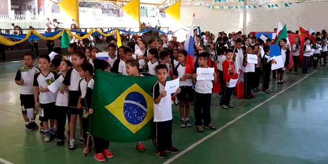 alunos da escola municipal Nai Molina, de Carapicuíba, desfilam em quadrapoliesportiva, divididos em grupos que representam os países participantes da Copa do Mundo