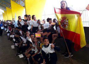 proefssora e alunos da escola municipal Nai Molina que repersentam a Espanha sorriem para a câmera, enquanto a outra metade da arquibancada acompanha o evento