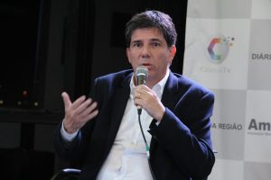 Claudio Piteri sentado e com o microfone na mão participando do debate