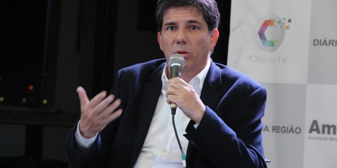 Claudio Piteri sentado e com o microfone na mão participando do debate