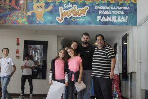 a diretoria do jornal Granja News posa para foto com família convidada diante da entrada para a Sala junior da Cinépolis do Iguatemi Alphaville