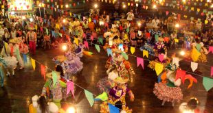 imagem de uma festa junina com bandeirinhas e várias pessoas dançando quadrilha
