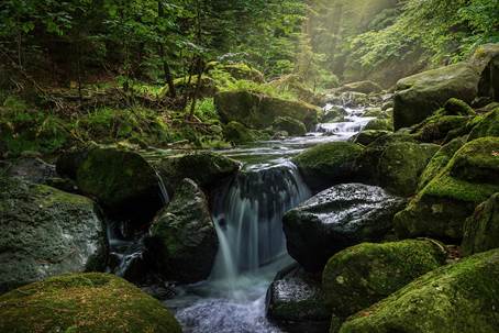 uma cachoeira caindo em meio a pedras cheias de limo
