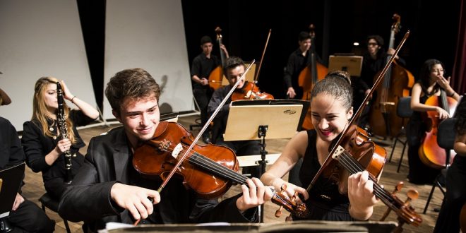 Alunos do Projeto Guri tocando violino, violoncelo e diante de partituras