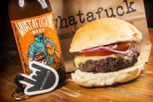 um hamburguer de costela da Whatafuck Hamburgueria ao lado de uma cerveja da casa