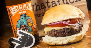 um hamburguer de costela da Whatafuck Hamburgueria ao lado de uma cerveja da casa