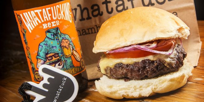 um hamburguer de costela da Whatafuck Hamburgueria ao lado de uma cerveja da casa