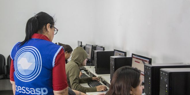 um grupo de pessoas acessando computadores do Acessa SP da Granja Viana, supervisionados por uma funcionária da iniciativa