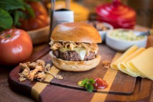 foto de um hamburguer com ingredientes dispostos ao redor