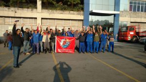 metalúrgicos da São Rafael num pátio com uma bandeira do SindMetal e os braços levantados