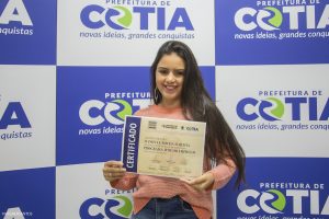 A aluna Danielle Rocha Martha exibe seu certificado para a câmera evento de formatura da turma do programa Time Emprego