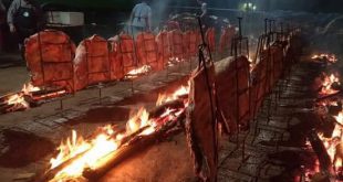 dezenas de costelas bovinas dispostas em espetos fincados no chão e margeando uma fogueira comprida