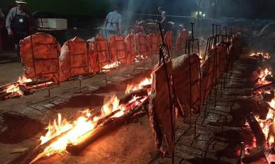 dezenas de costelas bovinas dispostas em espetos fincados no chão e margeando uma fogueira comprida