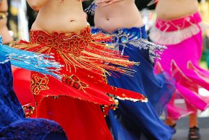 detalhe da cintura e das barrigas de quatro mulheres fazendo dança do ventre