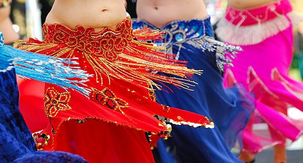 detalhe da cintura e das barrigas de quatro mulheres fazendo dança do ventre