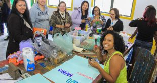 pessoas posam para a câmera volta de mesa com trabalhos