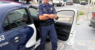 o guarda Russo de Cotia posa para foto ao lado de uma viatura da Guarda civil