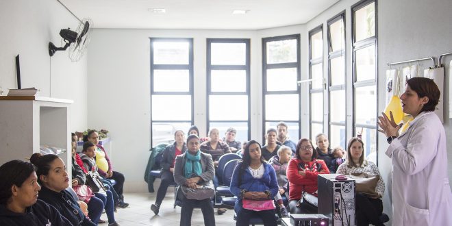 palestrante fala a um grupo de dezenas de participantes