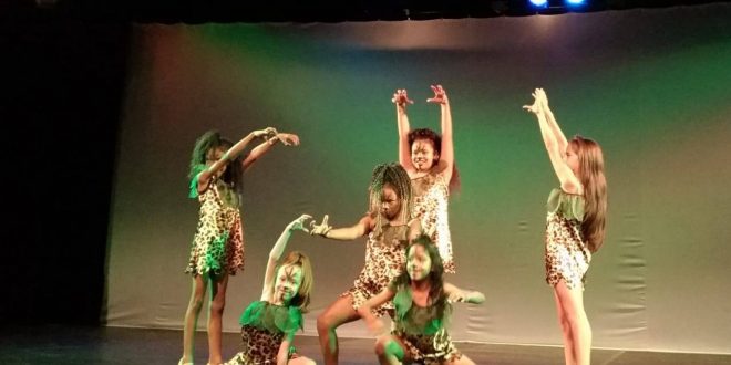 cena de espetáculo de teatro em Carapicuíba, com sete garotas se apresentando