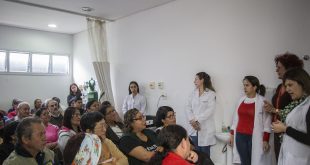 grupo de idosos acompanha explicações de profissionais de saúde em pequeno auditório