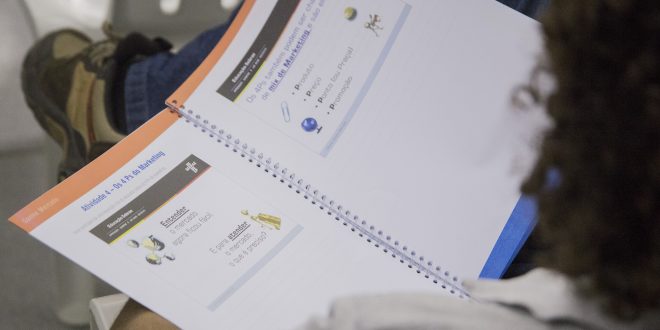 uma apostila do sebrae sendo manuseada por uma pessoa vista de costas e de cima