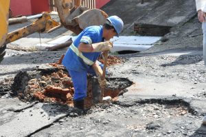 homem trabalhando em cratera em rua