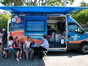 vã do sebrae móvel estacionada com duas pessoas sendo atendidas numa mesa ao lado dela