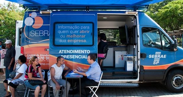 vã do sebrae móvel estacionada com duas pessoas sendo atendidas numa mesa ao lado dela