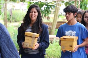 alunos segurando caixas em um jardim