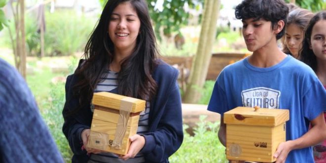 alunos segurando caixas em um jardim
