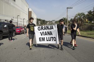 manifestantes caminhando com uma faixa escrito 'Granja Viana em luto'