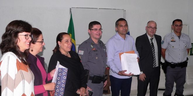duas representantes do movimento responsável pelo abaixo-assinado, Goreti, Fernandes, Almir, Marcos e Ricardo posam para foto; o documento está nas mãos de Almir