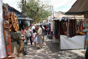 foto da Feira de Embu das Artes, com diversas bancas com produtos expostos e frequentadores caminhando em meio a elas