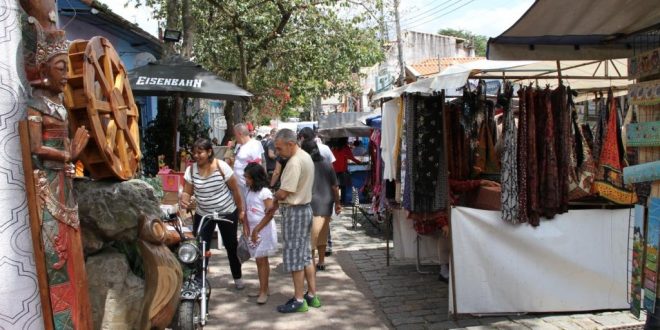 foto da Feira de Embu das Artes, com diversas bancas com produtos expostos e frequentadores caminhando em meio a elas
