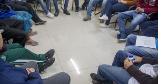 jovens que cumprem medidas socioeducativas sentados em círculo com o cantor e escritor Neto Poeta. Somente as pernas deles são mostradas