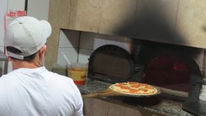 pizzaiolo prepara pizza na Pizza Estrela da Granja