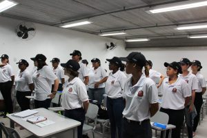 grupo de meninas em pé fazendo referência numa sala de aula