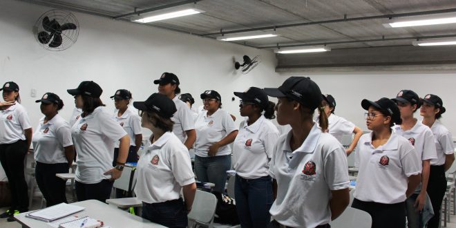 grupo de meninas em pé fazendo referência numa sala de aula
