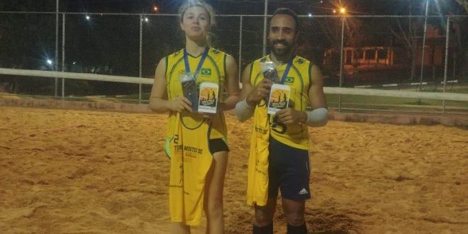 Gabriela e Marcos, a dupla campeã do 1º Torneio Misto de Vôlei de areia noturno, posa com medalhas