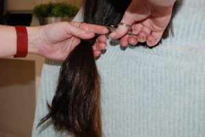 cabelos de uma menina sendo cortados para doação