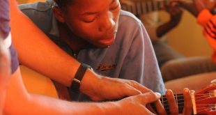 aluno recebendo instruções sobre como tocar o violão