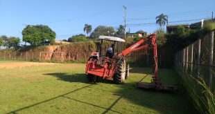 uma roçadeira cuidando do gramado do campo do jardim das oliveiras