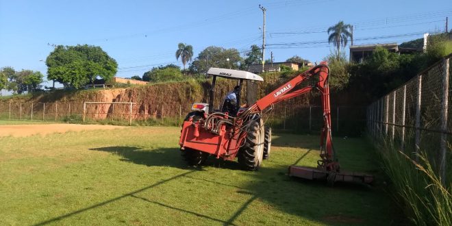 uma roçadeira cuidando do gramado do campo do jardim das oliveiras