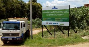 um caminhão estacionado ao lado da placa informativa referente à obra