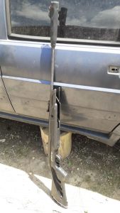 Espingarda de chumbo apoiada na lateral de um carro