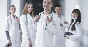 uma equipe médica sorri para a câmera no corredor de uma unidade de saúde