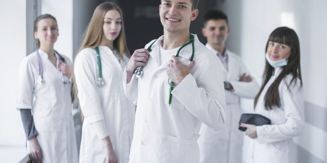 uma equipe médica sorri para a câmera no corredor de uma unidade de saúde