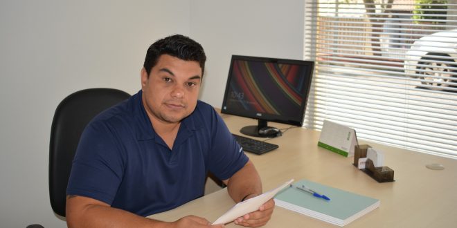 vereador rafael tanzi posa para foto sentado na mesa de seu gabinete