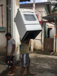morador carregando fogão em rua atingida pelas chuvas
